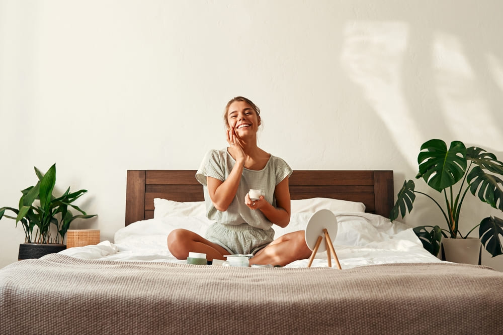 Woman sitting on bed following skincare ritual